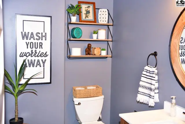 Modern bathroom with gray walls, floating shelves, and a decorative "Wash Your Worries Away" sign.