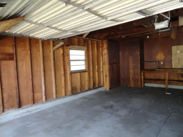 Interior of a garage with wood-paneled walls, concrete floor, and a workbench.