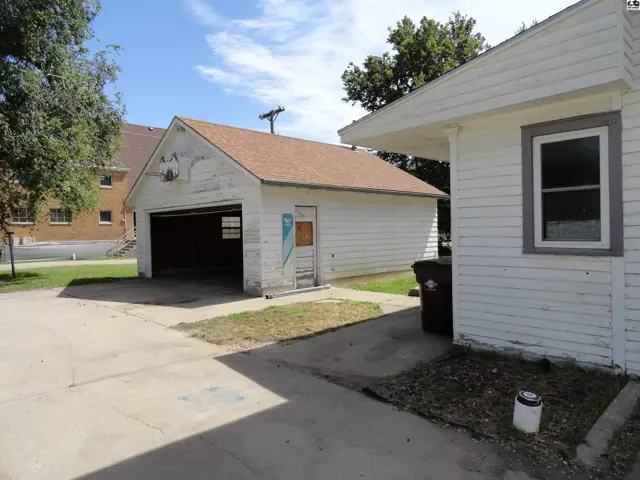 Exterior view of a detached white garage with a brown roof and a concrete driveway.