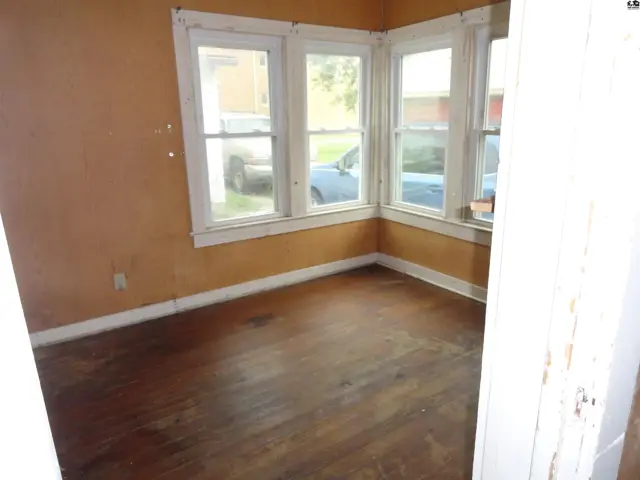 Corner room with bay windows, hardwood floors, and orange walls.