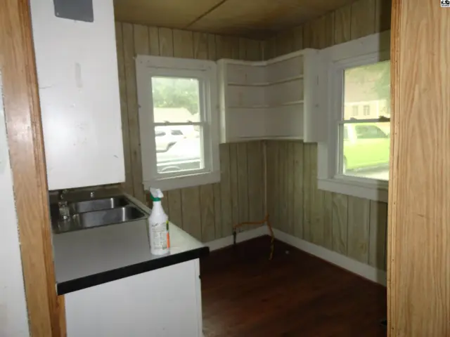 Compact kitchen with stainless steel sink, laminate countertops, and wood-paneled walls.