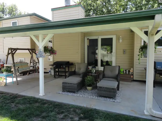 Covered patio with seating, swing, and grill offers outdoor living space.