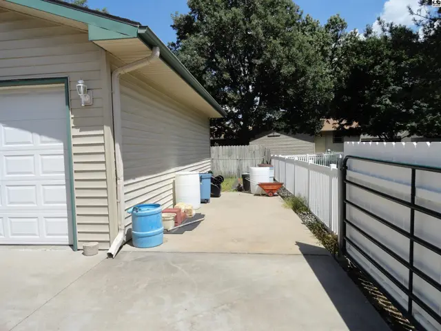 Exterior view of a beige vinyl-sided home with a white garage door and a white fence.