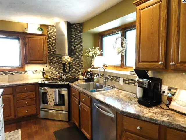 Spacious kitchen with oak cabinets, granite countertops, stainless steel appliances, and a decorative tile backsplash.