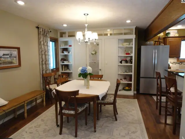 Dining room with a table, chairs, built-in shelving, and a chandelier.
