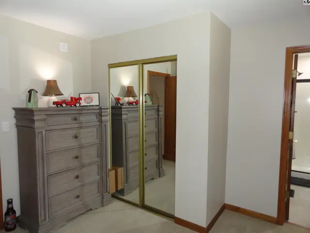 Bedroom with mirrored closet doors, gray dresser, and warm lighting.