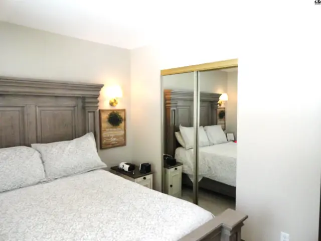 Spacious bedroom with a king-size bed, mirrored closet doors, and decorative wall sconces.