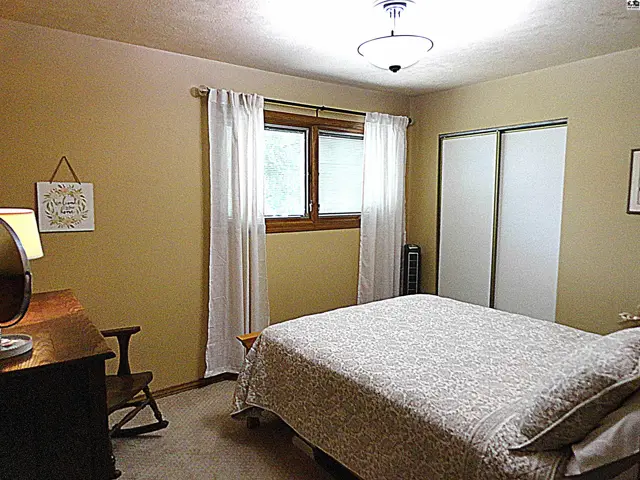 Cozy bedroom with a queen-sized bed, light tan walls, and a sliding closet.