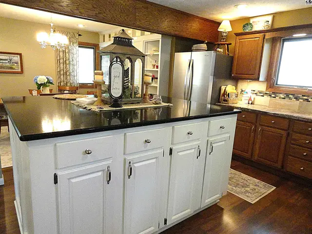 Spacious kitchen with a large white island, dark granite countertops, and rich wood cabinetry.