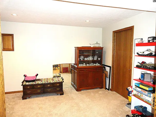 Spacious room with carpet, wood cabinets, a hutch, and a decorative bench.