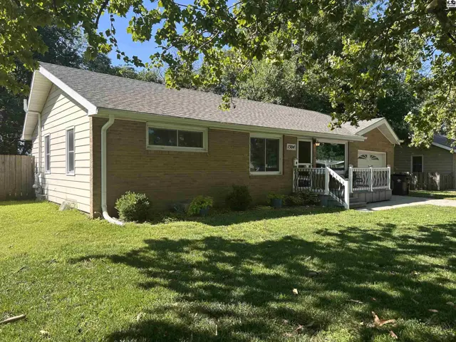 Brick and vinyl siding ranch home with a covered front porch and attached garage.