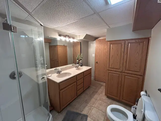 Spacious bathroom features a double vanity, glass-enclosed shower, and ample oak cabinetry.