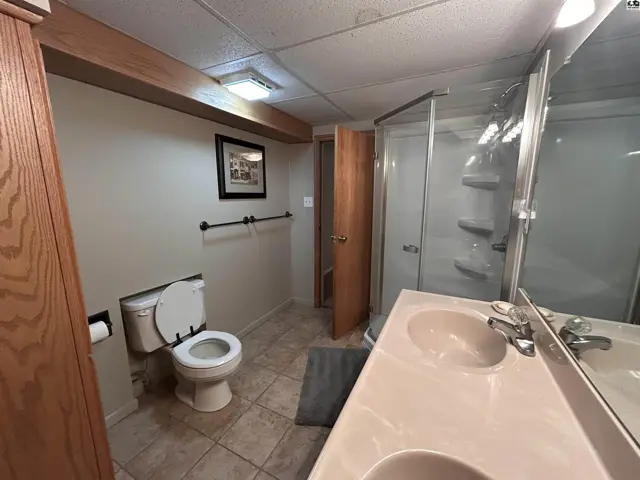 Spacious bathroom with a double vanity, tiled floor, and a glass-enclosed shower.
