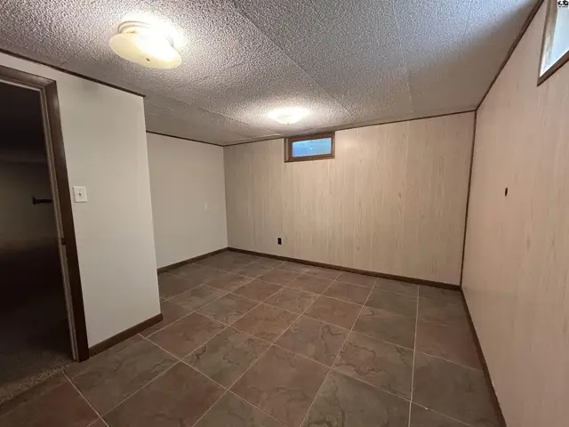 Empty room with textured walls, tiled floor, and a small window.