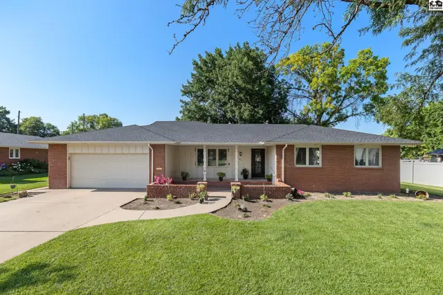 Brick ranch home with a white-trimmed entryway, attached garage, and manicured lawn.
