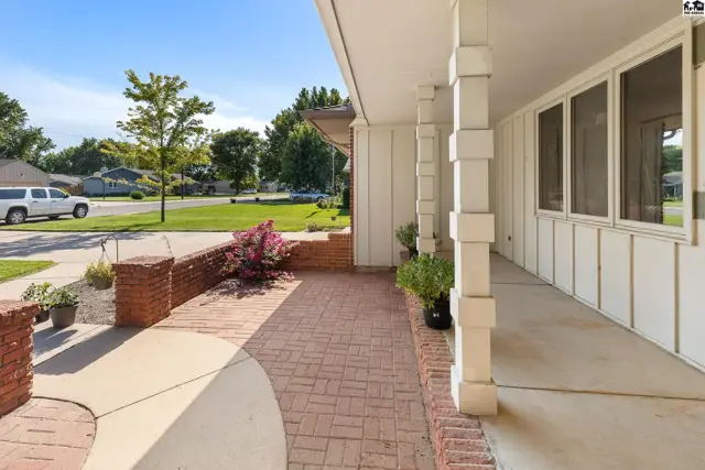Covered porch with white columns and brick walkway leading to a home entrance.