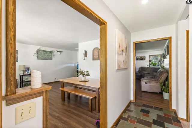 Hallway with wood trim and slate tile floor leads to dining area and living room.