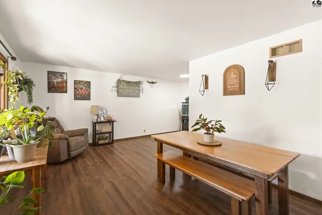 Spacious living and dining area with wood floors, a recliner, and a wooden table with bench.