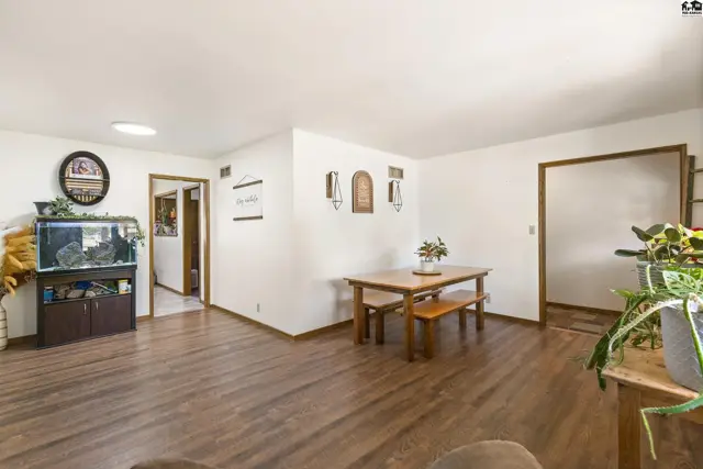 Spacious living and dining area with wood floors, a wooden table and benches, and a large aquarium.