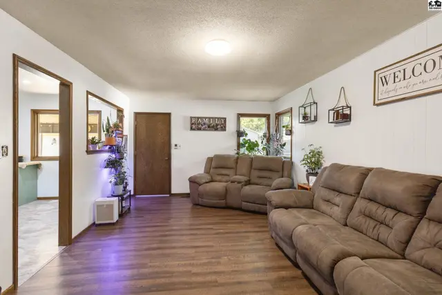 Spacious living room with plush brown recliners, wood-look flooring, and a "Welcome" sign.