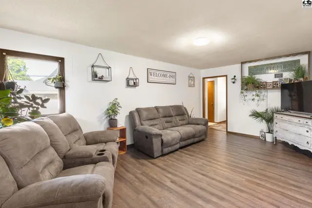 Living room with plush recliners, wood-look flooring, and decorative wall shelves.