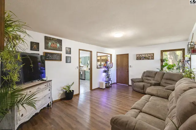Spacious living room with plush recliners, hardwood floors, and a white dresser holding a television.