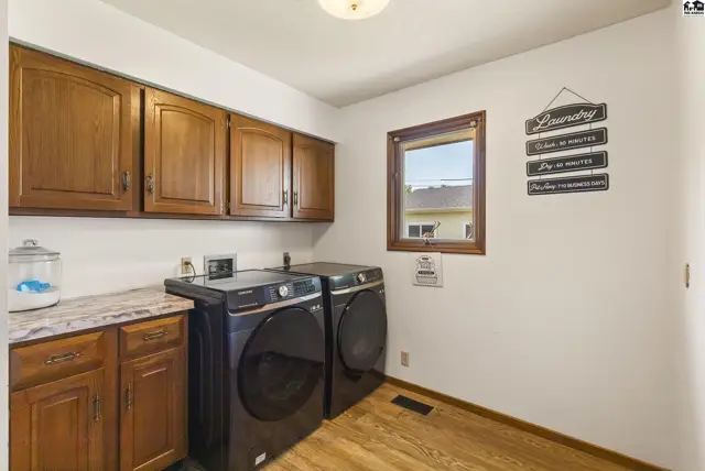 Laundry room with dark wood cabinets, granite-look countertop, and modern black washer and dryer.