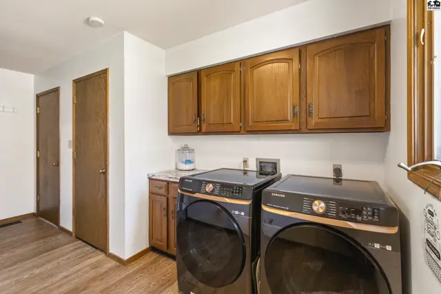 Laundry room with dark wood cabinets, granite countertop, and modern black washer and dryer.