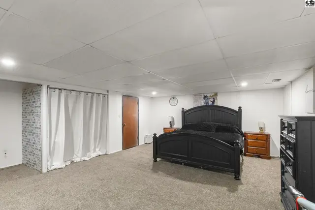 Spacious bedroom with a black bed frame, wood nightstands, and a textured accent wall.