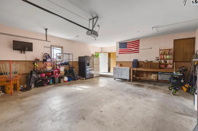 Spacious garage with concrete floor, storage shelves, workbench, and an American flag.