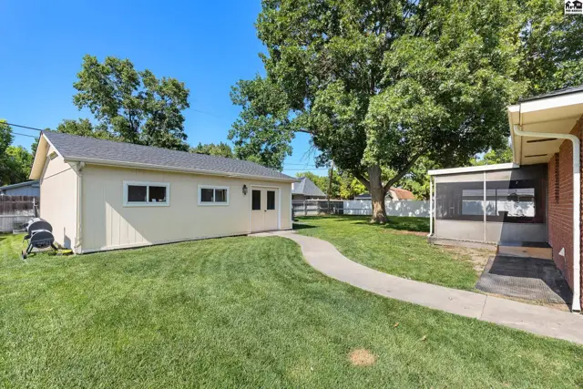 Exterior view of a cream-colored garage with a paved walkway through a manicured lawn.