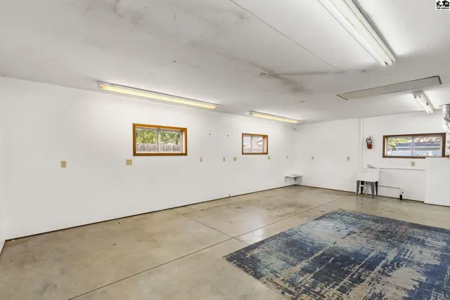 Spacious garage with concrete floors, white walls, and ample fluorescent lighting.