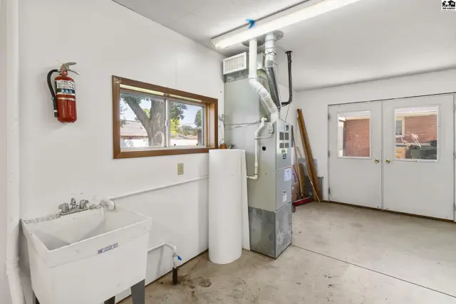 Utility room with a large sink, furnace, water heater, and double doors.