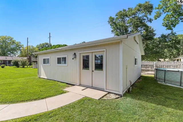 Exterior of a cream-colored detached garage with double doors and a small above-ground pool.