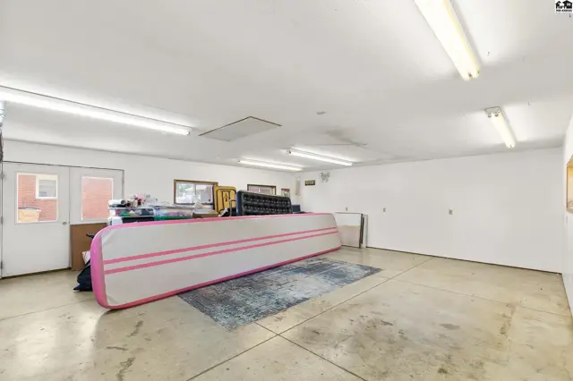 Spacious garage with concrete floors, white walls, and fluorescent lighting, featuring a large inflatable.