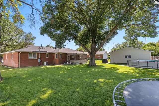 Spacious backyard with a large tree, screened porch, above-ground pool, and trampoline.