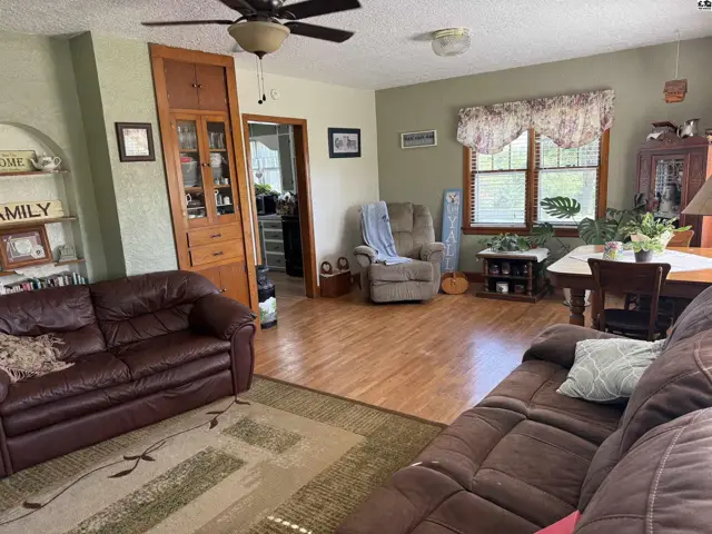 Living room with leather sofas, wood floors, built-in cabinetry, and a dining area.