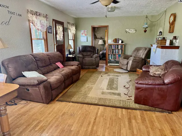 Living room with brown recliners, a sofa, hardwood floors, and a large area rug.