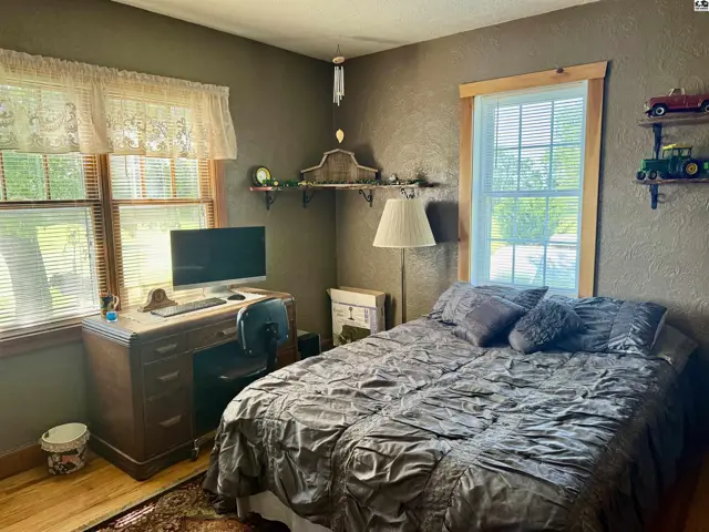 Cozy bedroom with a queen-size bed, wooden desk, and textured brown walls.