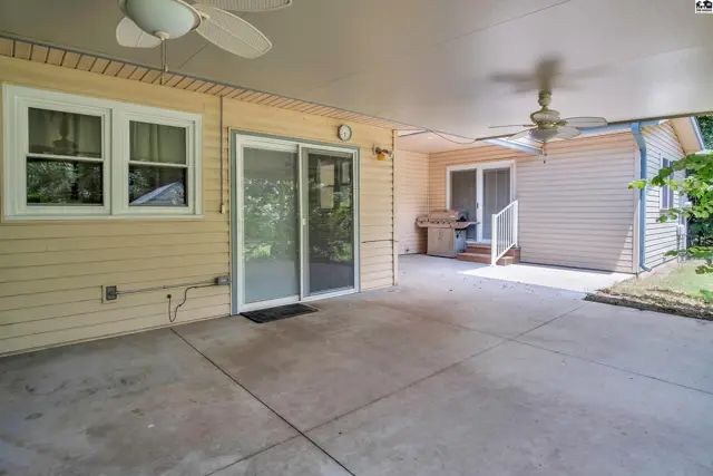 Spacious covered patio with concrete flooring, ceiling fans, and built-in grill.