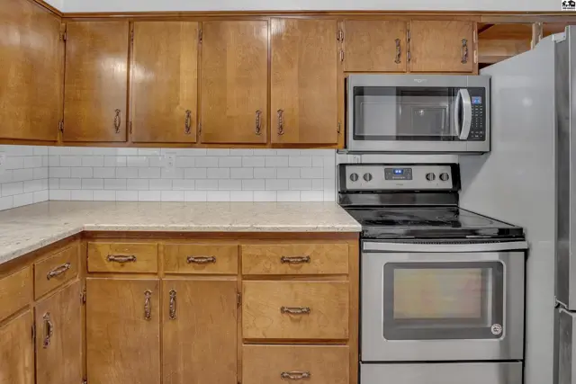 Kitchen with warm wood cabinets, white subway tile backsplash, and stainless steel appliances.