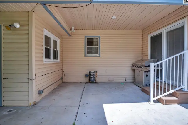 Covered patio with concrete floor, beige siding, and a stainless steel grill.