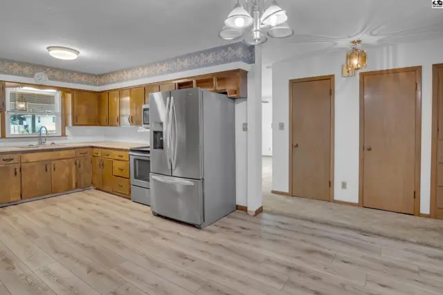 Spacious kitchen with light wood cabinets, stainless steel appliances, and light wood-look flooring.