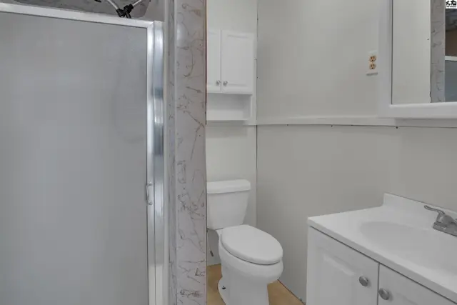 Modern bathroom with a frosted glass shower, white vanity, and toilet.