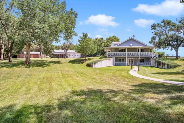 Spacious two-story home with a wraparound porch, nestled on a grassy lot with mature trees.