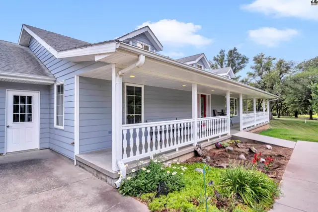 Light blue siding and white railings adorn a wraparound porch on this charming home.