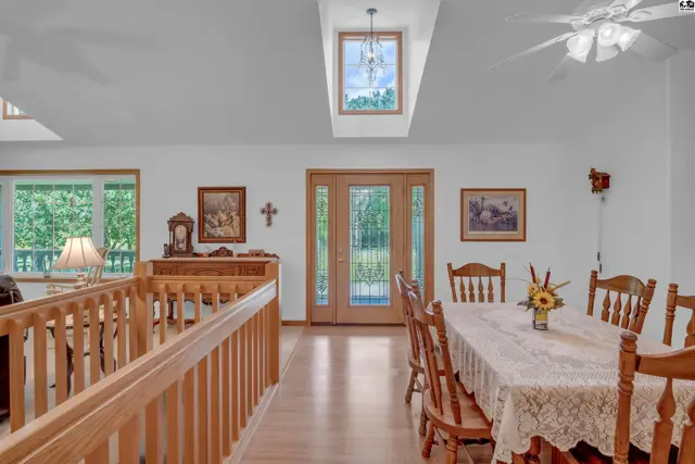 Spacious dining room with a vaulted ceiling, skylight, wood accents, and a view of the outdoors.