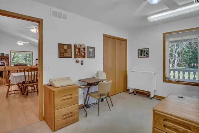Bright home office with a sewing station, wooden desk, and view of a dining area.