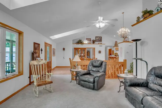Spacious living room with vaulted ceilings, a skylight, leather recliner, and wood accents.