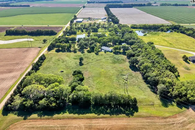 Expansive rural property features a home, trees, ponds, and surrounding agricultural fields.